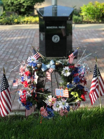 two flags and a patriotic wreath in front of the monument. the memorial says minerva park on the front