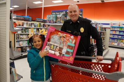 girl shows off playset picked out in front of shopping cart with officer 