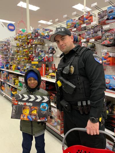 child shows off lego toy in aisle of target with officer holding a basket 