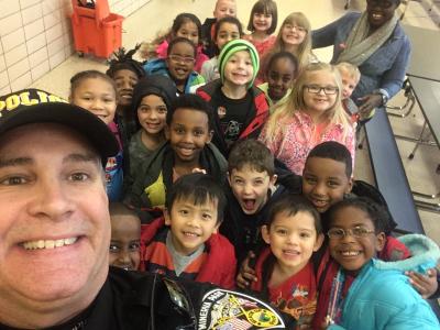 A selfie of Chief Delp and students at Hawthorne Elementary smiling in the cafeteria