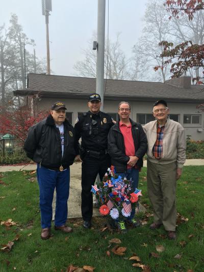 three residents and the police chief standing in front of the veterans memorial 