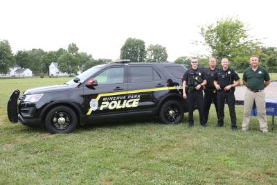Minerva Park police cruiser on left and four officers standing next to the cruiser 