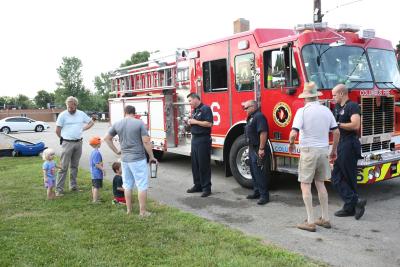 children talk to ems employees outside of fire truck in parking lot 