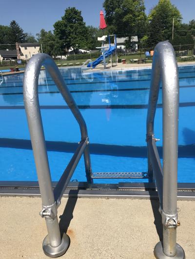 ladder to get into pool and pool slide in the background 